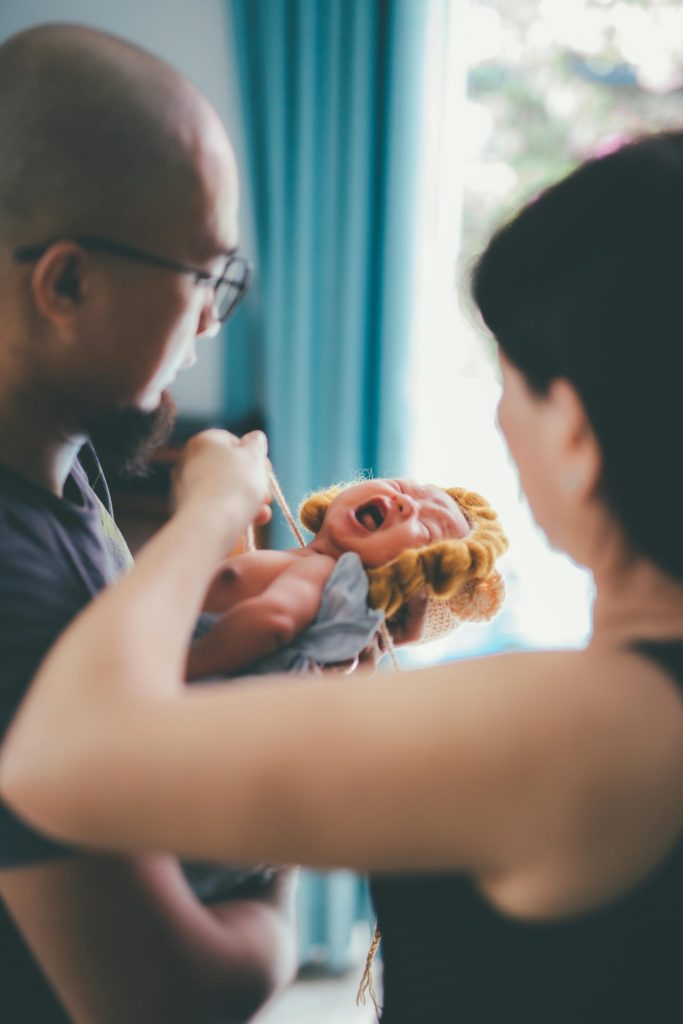 A heartwarming moment of parents comforting their crying baby in a cozy indoor setting.